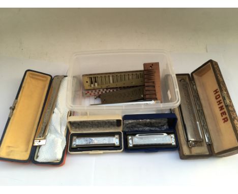 A small box of harmonicas and and harmonica parts.