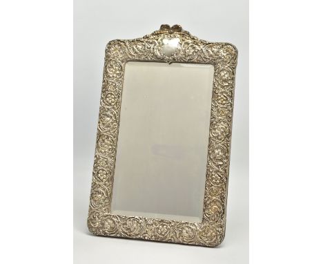 AN EDWARDIAN SILVER MOUNTED EASEL BACK MIRROR, embossed with a ribbon over a vacant cartouche, pierced foliate scroll decorat