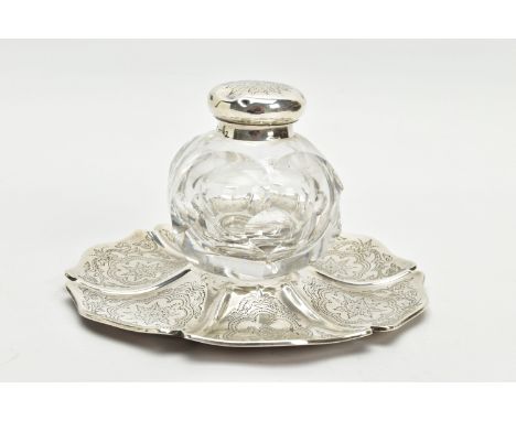 A VICTORIAN SILVER AND GLASS INKWELL ON STAND, of wavy circular outline, foliate engraved decoration and with crest and inscr