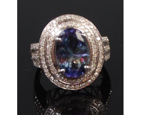 A contemporary 14ct white gold tanzanite and diamond set cocktail ring, the oval cut tanzanite weighing approx 4.25ct, in a t