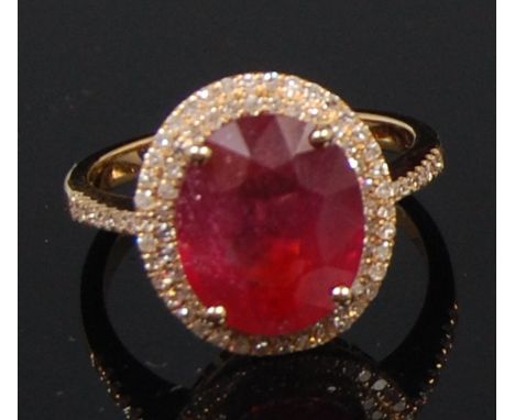 A 14ct yellow gold ruby and diamond dress ring, arranged as a centre oval cut ruby weighing approx 5.6ct, within a stepped tw