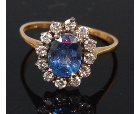 A ladies 18ct gold sapphire and diamond cluster ring, the four claw set oval cut sapphire weighing approx 2.8ct, in a surroun