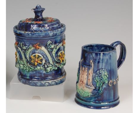 An Edward Bingham Castle Hedingham Pottery jar and cover, decorated with scrolling flowers and foliage on a blue glazed groun