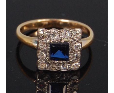 A ladies Art Deco 18ct gold sapphire and diamond dress ring, arranged as a centre square cut sapphire weighing approx 0.45ct,