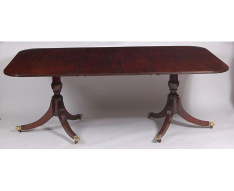 A mahogany twin pillar dining table, early 20th century in the Regency manner, having four extra leaves, the top with reeded 