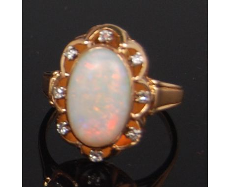 A ladies 18ct gold opal and diamond set dress ring, arranged as a cabochon opal within a surround of 8x four claw set small b