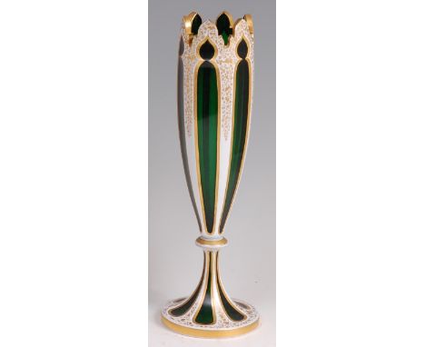 A late 19th century Bohemian overlay on green glass pedestal vase, thumb-cut and of slender baluster form, heightened in gilt