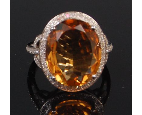 A contemporary 14ct white gold citrine and diamond set cocktail ring, arranged as a centre four claw set oval cut citrine wei