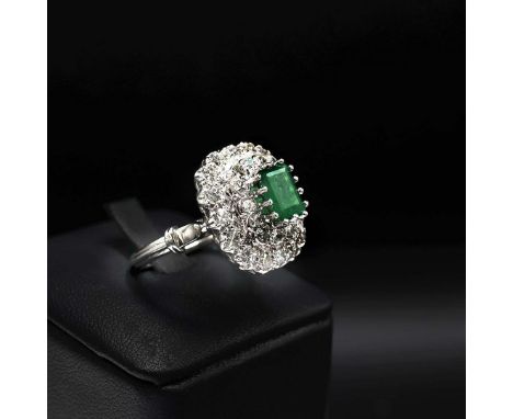 A WHITE METAL EMERALD AND DIAMOND RING. the step-cut emerald and diamond double halo ring, the emerald of approximately 1.00 