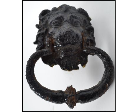 A 19th century cast iron door knocker in the form of a lion having an ebonised painted finish. Longest measures 46 cm.