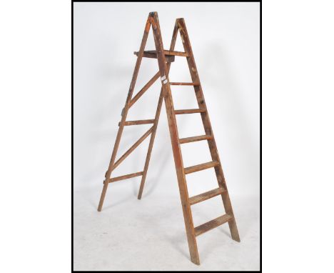 A vintage Industrial 20th century pine workmans ladders with a-frame supports and folding having remains of paintwork. Measur