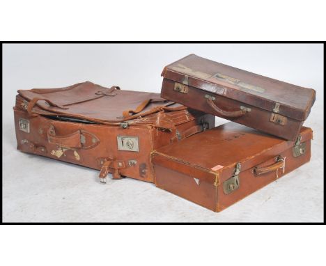 A group of vintage 20th century leather luggage to include a large suit case with dual lock having stamps for Shanghai and tw