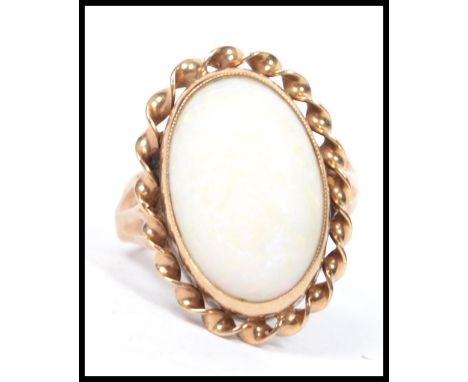 A hallmarked 18ct gold opal ring having a large opal cabochon with rope twist border, weighs 3.8 grams size G.