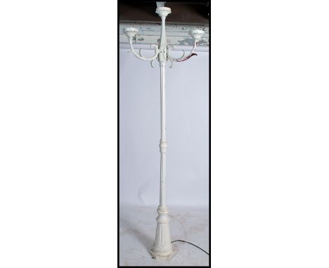 A Victorian style garden standard lamp in the form of a Victorian street lamp raised on a hexagonal base with three scrolled 