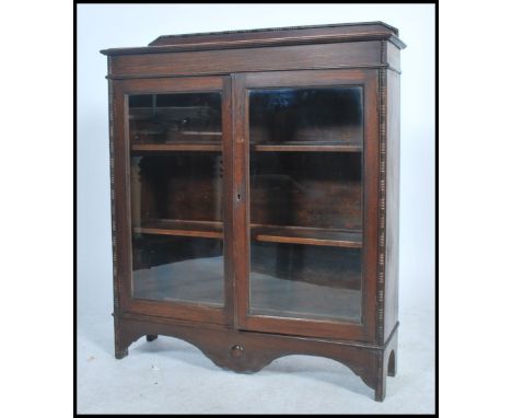 A 1930's oak bookcase display cabinet raised on bracket feet having twin doors with shelves inside having gallery top. Measur