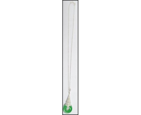 A 20th century silver and jade pendant complete with necklace chain. The Jade pendant of circular pierced roundel form. 18" l