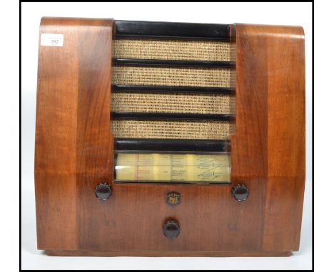 A vintage 20th century Peto Scott walnut cased valve radio. Having a central speaker to the front, knobs and dials below. Mea