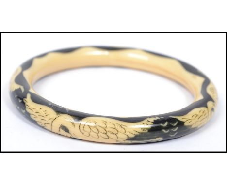 A vintage 20th century cream and black lucite bangle bracelet depicting storks in flight.