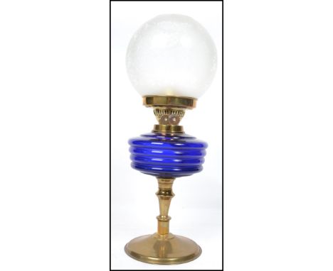An early 20th century brass and blue glass oil lamp complete with a frosted glass shade. The brass stand with blue glass rese