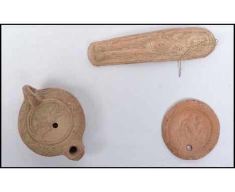 A group of three Roman stone items to include a devotional figurine, medallion coin and lamp base.