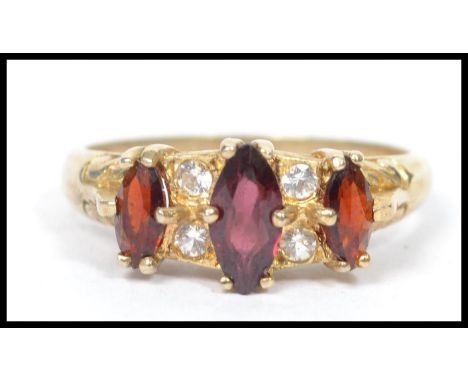 A vintage 20th century silver gilt three stone garnet ring having four inset clear stones. Weighs 3.1 grams size P.&nbsp;