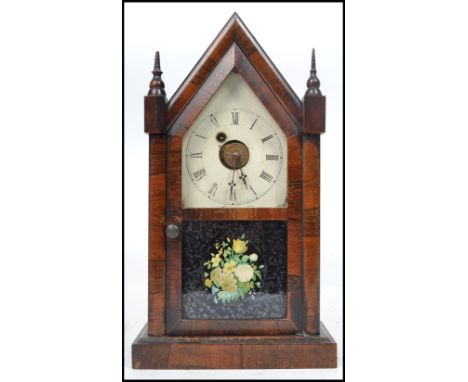 A 19th century American gingerbread mahogany cased mantle alarm clock by Waterbury having an enamel face, roman numeral chapt