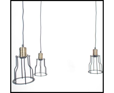 A group of three vintage industrial style pedant ceiling cage lights, black wire work cages with attached ceiling rose.