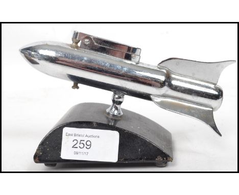 A vintage 20th century retro 1960's chrome plated novelty space rocket table lighter raised on ebonised base. Measures 11 cm 