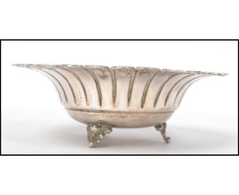 A sterling silver 925 stamped bon bon dish of scalloped form raised on tripod feet. Measures 5 cm high and 14 cm diameter.