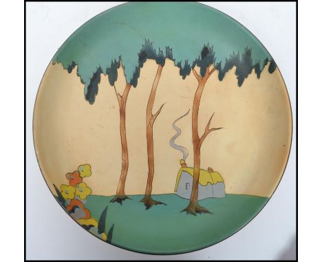 A vintage 20th century Art Deco hand decorated wall charger in the manner of Clarice Cliff. Decorated with a cottage with smo