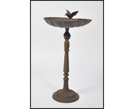 A vintage 20th century cast iron pedestal bird bath. The scalloped shaped bath surmounted with a Bluebird. Remnants of origin