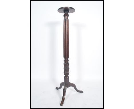 A 19th century tall oak carved torchere, with acanthus and scroll carved decoration upon a turned column and tripod downswept