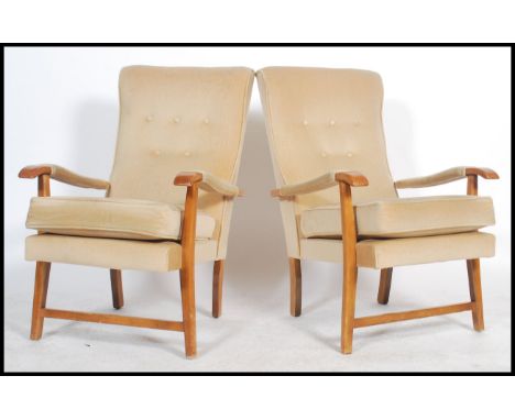 A pair of retro 20th century open framed beech wood fireside armchairs each being upholstered with a chintz button back velou