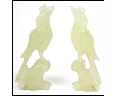 A pair of Chinese 20th century carved jade figurines of songbirds raised in perch plinth bases to each. Measures 11 cm high.