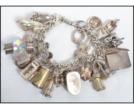 A hallmarked silver charm bracelet having many charms to include a shoe, phone box, man playing guitar, hover craft, bottle, 