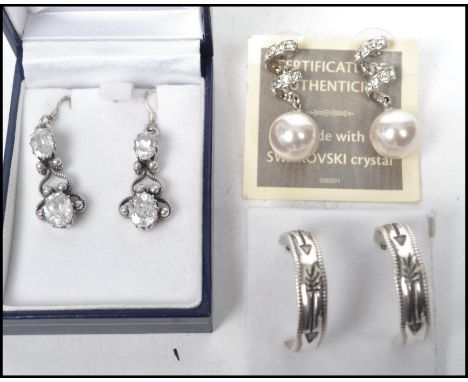 A group of three pairs of sterling silver earrings to include a silver drop earring set with four stones in detailed surround