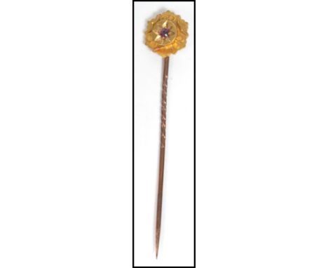 A 15ct gold and ruby stick pin complete in the presentation case. The pin with central ruby stone on flower head setting. wei