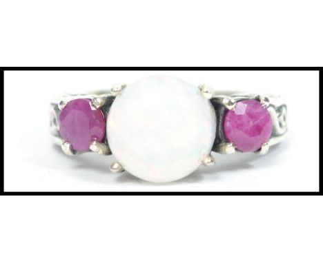 A ladies silver three stone ring with central opal having adjacent garnet prong setting. Size N / Weight 5g.