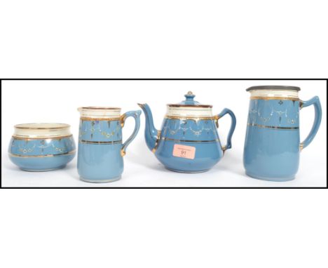 A 19th century Victorian four piece stone ware ceramic tea service having a blue ground with gilt and white detailing consist