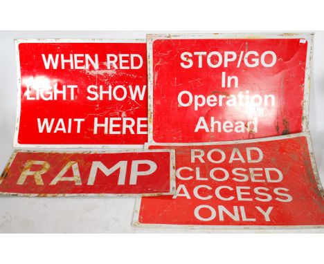 A collection of four retro 20th century metal road work signs, white lettering on red ground reading when Red Light Shows Wai
