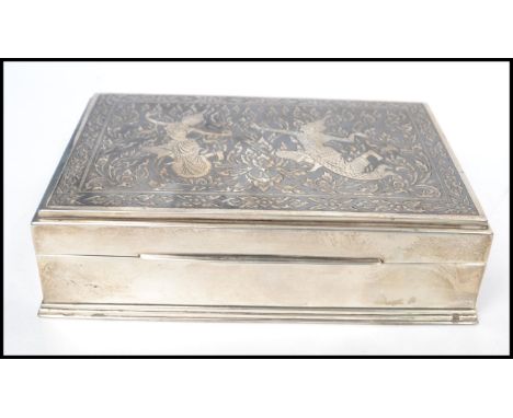 A vintage 20th century Thai sterling silver cigarette box having Niello&nbsp;decoration to id depicting figures and leaves, t