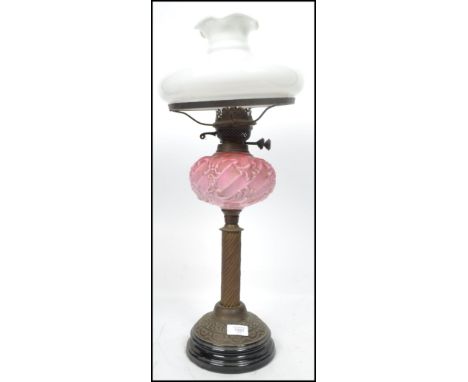 A 19th century Victorian oil lamp raised on a stepped circular base with readed column cranberry glass recess and brass suppo