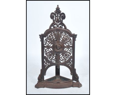 A 19th century Victorian cast iron umbrella stick stand being pierced decorated with scrolls and leaves with circular cherub 