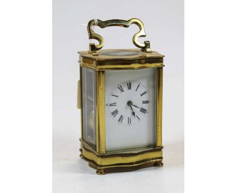 An early 20th century lacquered brass cased carriage clock, of serpentine shape, having an enamelled dial with Roman numerals