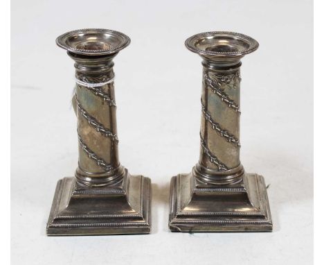 A pair of late Victorian silver candlesticks, each having a removable sconce to a circular stem, relief decorated with acorns