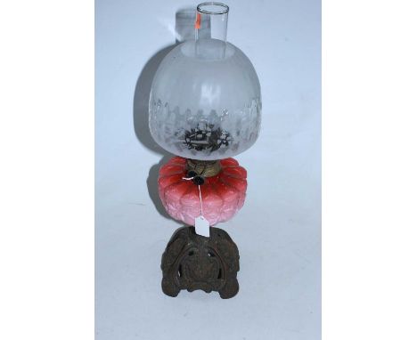 A Victorian pedestal oil lamp having a domed glass shade above a pink tinted font on pierced cast iron base, height 50cmCondi