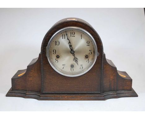 A 1930s oak cased mantel clock, having a silvered dial with Arabic numerals and chiming movement 