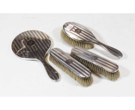 A silver backed hand mirror with engine turned decoration together with a matching hairbrush and two clothes brushes (4)
