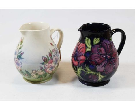A Moorcroft pottery jug in the Anenome pattern on dark blue ground with typical tube lined floral decoration, impressed Moorc