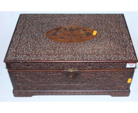 A large late 19th century Burmese teak dressing box, the whole profusely carved with foliage, the oval cartouche with brass f